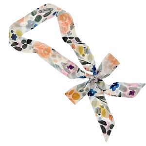 May include: A floral patterned scarf with a bow. The scarf features a watercolor design with peach, blue, yellow, and purple flowers on a white background. The scarf is tied in a bow at the center.