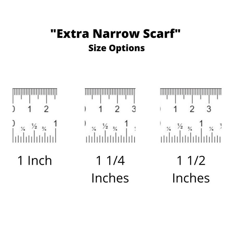May include: Three rulers showing different widths for a scarf: 1 inch, 1 1/4 inches, and 1 1/2 inches. "Extra Narrow Scarf" is written above the rulers.