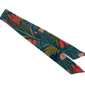 May include: A teal blue fabric scarf with a floral pattern featuring red, orange, and yellow flowers and leaves.