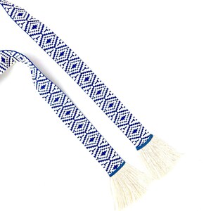 May include: Two blue and white patterned fabric ribbon ties with white fringe ends.