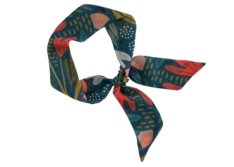 May include: A teal blue patterned scarf with red, pink, and yellow floral designs. The scarf is tied in a knot.