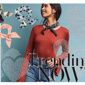May include: A woman wearing a red long-sleeved shirt with a blue and white patterned scarf tied around her neck. She is smiling and looking to the right. The background is a light blue with the words "Trending NOW" in black.
