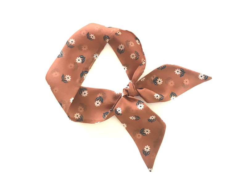 May include: A brown floral patterned hair scarf tied in a bow.