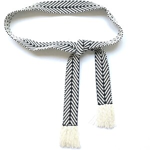 May include: A black and white chevron patterned belt with white fringe tassels.