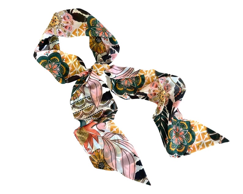 May include: A long, narrow scarf featuring a vibrant, multi-colored floral and geometric pattern. The design includes shades of deep green, mustard yellow, soft pink, and black, arranged in repeating mandala-like motifs and leaf shapes.