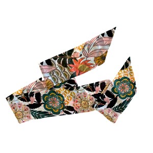 May include: A long, narrow scarf featuring a vibrant botanical and geometric pattern. The design includes stylized flowers in shades of coral, teal, and gold, set against a black background with white and yellow accents, creating a complex visual.