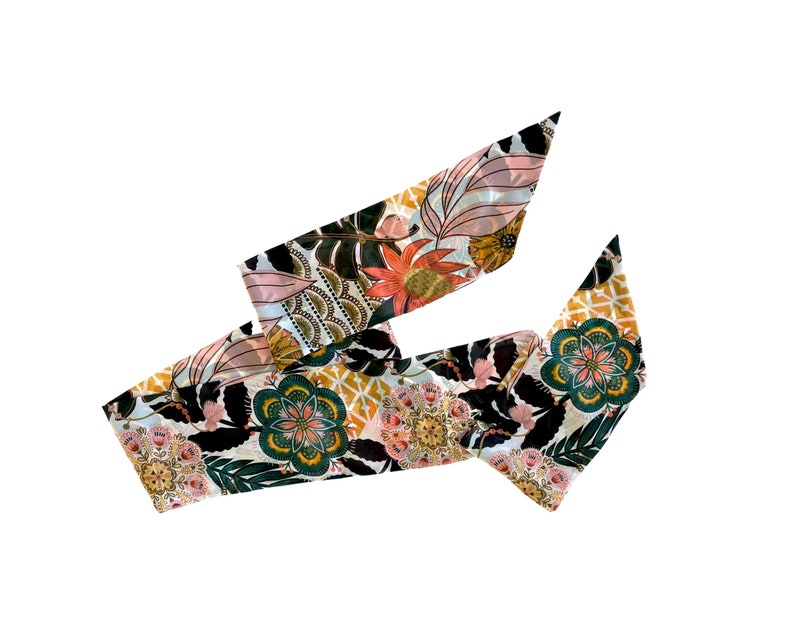 May include: A long, narrow scarf featuring a vibrant botanical and geometric pattern. The design includes stylized flowers in shades of coral, teal, and gold, set against a black background with white and yellow accents, creating a complex visual.