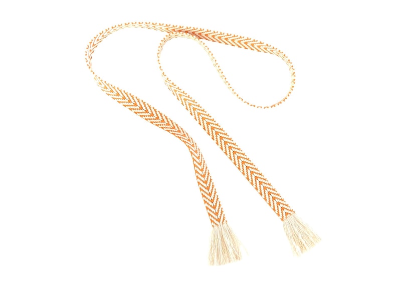 May include: A long, thin, woven cord with a chevron pattern in brown and white. The cord has tassels at each end.
