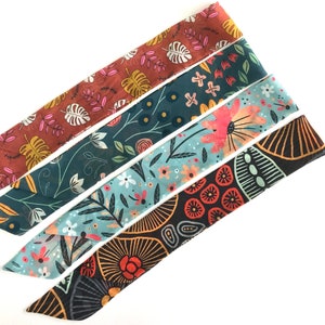 May include: Four fabric headbands with different floral patterns. The headbands are in shades of red, orange, teal, blue, and black.