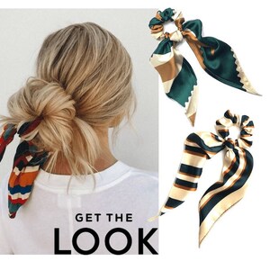 May include: Three colorful patterned hair scrunchies with long tails. The scrunchies are made of satin fabric and have a green, brown, and white color scheme. The scrunchies are tied in a bow and are shown on a white background.