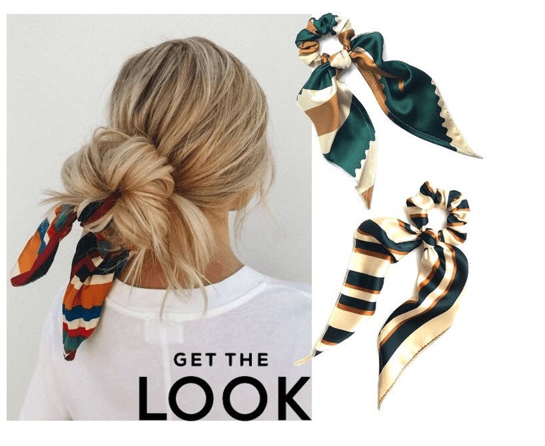 May include: Three colorful patterned hair scrunchies with long tails. The scrunchies are made of satin fabric and have a green, brown, and white color scheme. The scrunchies are tied in a bow and are shown on a white background.