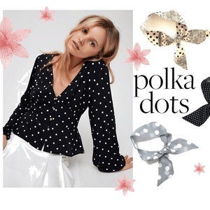 May include: A black and white polka dot blouse with long sleeves and a V-neckline. The blouse has a fitted bodice and a slightly flared hem. The model is wearing the blouse with a white skirt. The image also includes three polka dot headbands in different colors: black and white, gray and white, and beige and black.
