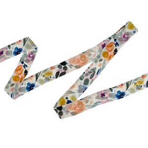 May include: A floral patterned ribbon in a watercolor style. The ribbon features a white background with colorful flowers in shades of blue, orange, yellow, and purple. The ribbon is folded in a zig-zag pattern.