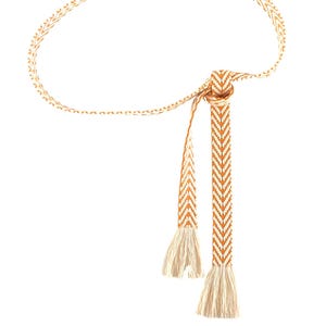 May include: A woven orange and white belt with tassels. The belt is made of a chevron pattern.
