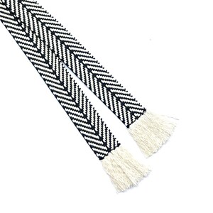 May include: Black and white chevron patterned ribbon with white fringe on both ends.