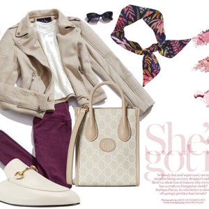 May include: A fashion flat lay featuring a beige suede jacket, a white t-shirt, burgundy pants, white leather loafers with gold hardware, a beige and brown patterned tote bag, a snakeskin clutch, gold hoop earrings, a floral patterned scarf, and a pink eyeshadow palette. The text "She's got it" is visible in the image.