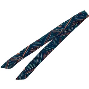 May include: A dark blue fabric scarf with a geometric pattern in shades of teal, pink, and white.