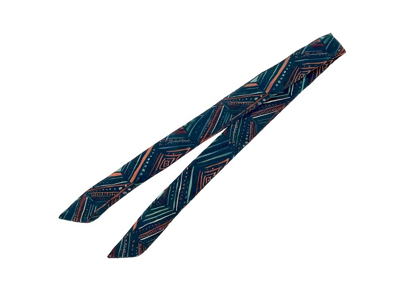 May include: A dark blue fabric scarf with a geometric pattern in shades of teal, pink, and white.