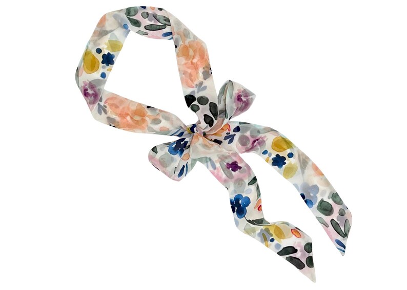 May include: A floral patterned scarf with a bow. The scarf features a watercolor design with flowers in shades of pink, yellow, blue, and green on a white background. The scarf is tied in a bow.