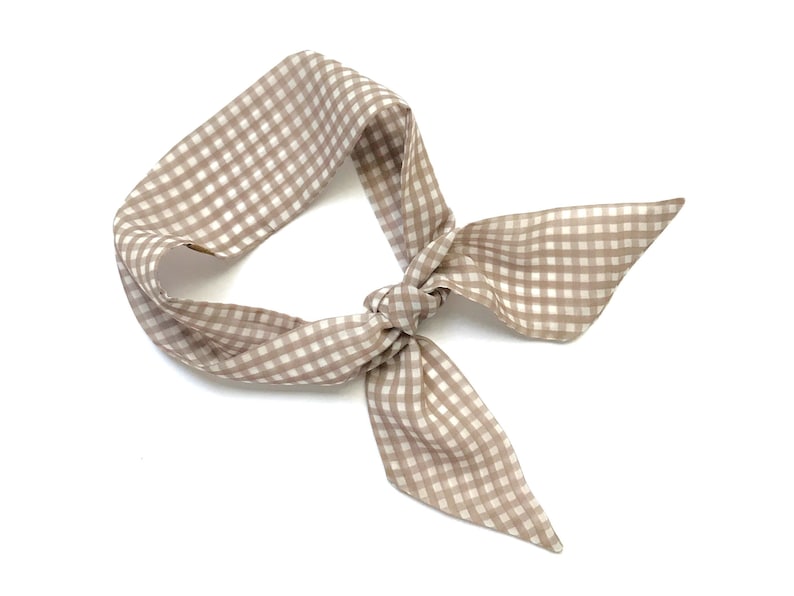 May include: A brown and white gingham hair scarf tied in a bow.