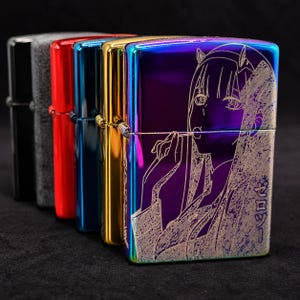May include: A row of five rectangular metal lighters in black, grey, red, blue, gold, and a rainbow iridescent finish. The front-most rainbow lighter features a laser-engraved anime character illustration and Japanese text characters.