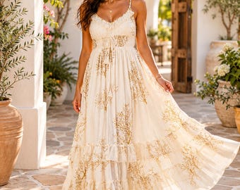 May include: A floor-length cream-colored maxi dress featuring a delicate gold-toned coral branch print, thin spaghetti straps, a ruffled neckline, a cinched waist with a drawstring tie, and a tiered skirt with multiple ruffled layers.
