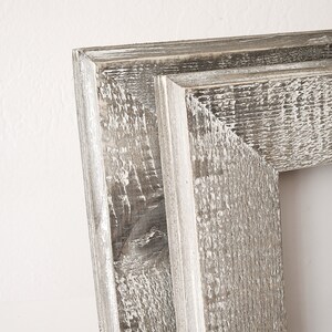 May include: Close-up of a rustic wooden picture frame with a distressed white paint finish. The frame has a simple, rectangular shape and a slightly raised edge.
