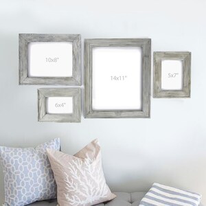 May include: Four rustic wooden picture frames in various sizes, with whitewashed paint. The frames are arranged on a white wall, with the largest frame measuring 14x11 inches, the next largest 10x8 inches, the next 6x4 inches, and the smallest 5x7 inches.