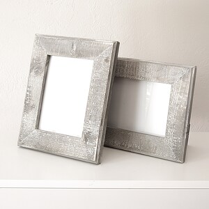 May include: Two rustic gray wooden picture frames with a white mat and a white background.