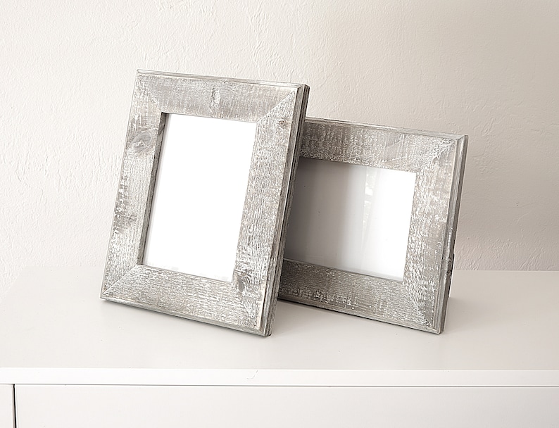 May include: Two rustic gray wooden picture frames with a white mat and a white background.
