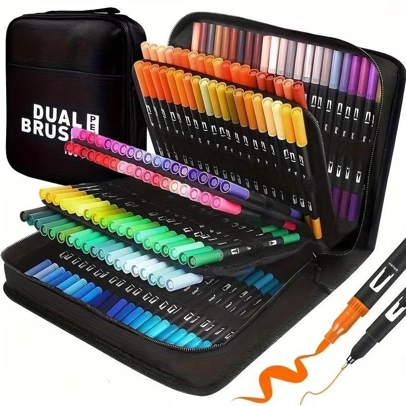 May include: A black zippered case labelled "DUAL BRUSH" holds a collection of dual-tip brush pens in a variety of colours. The pens are neatly arranged, displaying a rainbow of hues. Two pens are shown with ink strokes, demonstrating the pen's dual tip functionality.
