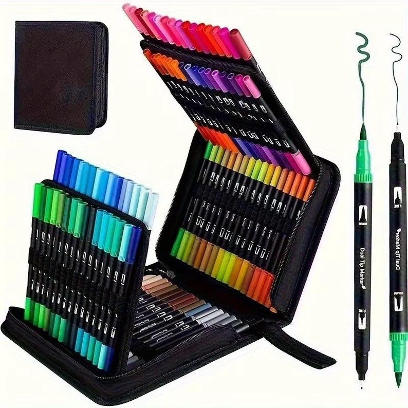 May include: A black zipped case containing a wide array of dual-tip markers in various colours. The markers are organised in rows, displaying a spectrum of hues. Two markers stand upright, with the words "Dual Tip Marker". A separate black case is also visible.