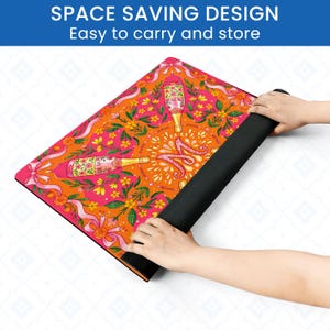 May include: A colorful yoga mat with a champagne bottle design. The mat features a vibrant orange and pink floral pattern with champagne bottles and ribbons. The text "SPACE SAVING DESIGN Easy to carry and store" is at the top.