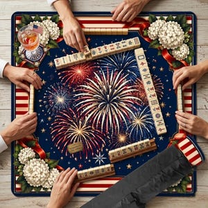 May include: A Mahjong game in progress on a navy blue mat with a fireworks design. The mat has red and white stripes around the edges and white floral accents. Mahjong tiles are arranged around the mat, with hands holding the tiles. A cocktail with an American flag is on the mat.