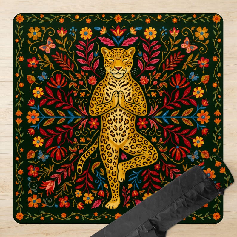 Puede incluir: Una esterilla de yoga con un leopardo dorado en postura de &aacute;rbol, rodeado de un dise&ntilde;o floral con mariposas. La esterilla tiene un fondo verde oscuro con flores rojas, naranjas y amarillas. Se incluye una funda de transporte negra.