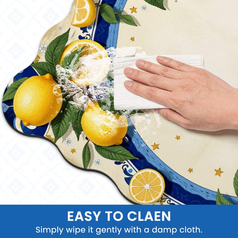 K&ouml;nnte beinhalten: Eine dekorative Matte mit einem Zitronen- und Bl&auml;ttermuster, mit einem blau-wei&szlig;en Rand. Die Matte wird mit einem feuchten Tuch gereinigt. Der Text "EASY TO CLEAN" ist sichtbar.