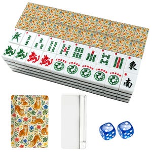 May include: A set of white mahjong tiles featuring green and red dragon symbols, numbered bamboo patterns, joker labels, and Chinese characters. The back of the tiles displays a colourful tiger and floral pattern. Includes two blue translucent dice.