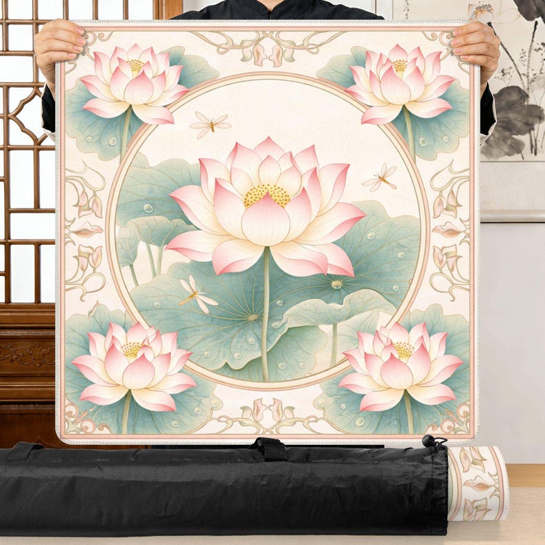 Puede incluir: Esterilla de yoga cuadrada con un dise&ntilde;o floral de flores de loto rosas, hojas verdes y lib&eacute;lulas sobre un fondo crema, enmarcada por un borde decorativo. Una bolsa de transporte negra est&aacute; en la parte inferior.