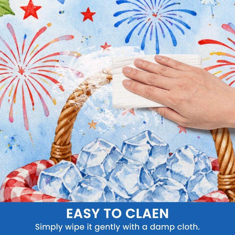 May include: A hand wipes a surface with a white cloth. The surface has a watercolor design of fireworks, stars, and a picnic basket filled with ice. Text at the bottom reads "EASY TO CLEAN" and "Simply wipe it gently with a damp cloth."