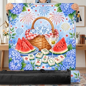 May include: A picnic blanket with a watercolor design featuring a picnic basket filled with ice, watermelon slices, a martini, and Mahjong tiles. The background includes fireworks, blue hydrangeas, and red stars.