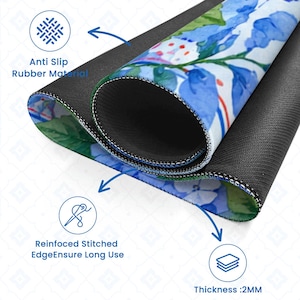 May include: A rolled-up mousepad with a floral design featuring blue and white flowers. The mousepad has a black, anti-slip rubber base and reinforced stitched edges. The thickness is 2mm.