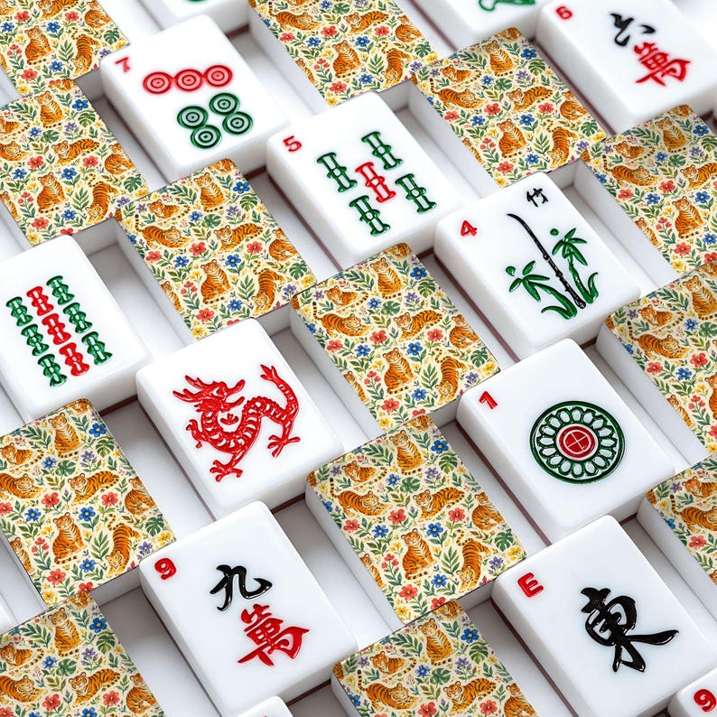 May include: A collection of mahjong tiles featuring white faces with red, green, and black traditional symbols, numbers, and characters, interspersed with tiles displaying a repeating pattern of orange tigers and blue flowers on a cream background.
