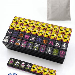 Peut inclure: Un jeu de tuiles de mah-jong noir et jaune sur le thème d'Halloween avec des illustrations de chats, chiens, fantômes et citrouilles, accompagné d'un sac de rangement gris à cordon et deux dés bleus. Les tuiles portent des chiffres et JOKER.