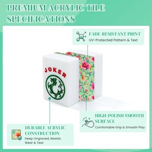 K&ouml;nnte beinhalten: Zwei wei&szlig;e Acryl-Mahjong-Spielsteine mit einem gr&uuml;nen Drachenemblem und dem roten Schriftzug JOKER. Die Spielsteine zeigen an der Seite ein florales Muster mit rosa und orangefarbenen Blumen auf gr&uuml;nem Grund. Textbeschriftungen weisen auf die langlebige Konstruktion, den lichtbest&auml;ndigen Druck und die hochglanzpolierte, glatte Oberfl&auml;che hin.