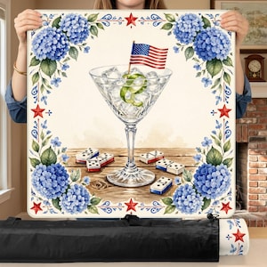 May include: A decorative square table featuring a watercolor illustration. The design includes a martini glass with an American flag, ice, and a lime twist, surrounded by blue hydrangeas, red stars, and dominoes. The table is held by a person.