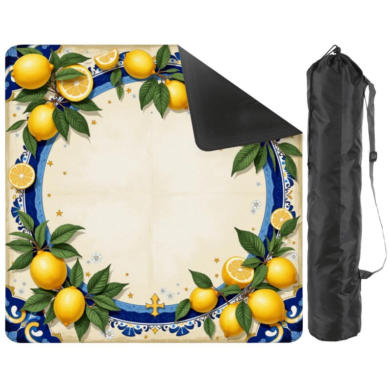 K&ouml;nnte beinhalten: Eine Picknickdecke mit Zitronen- und Bl&auml;ttermuster, mit blau-wei&szlig;em Rand. Die Decke ist in einer schwarzen Tragetasche mit Schultergurt aufgerollt. Die Decke hat einen cremefarbenen Hintergrund.
