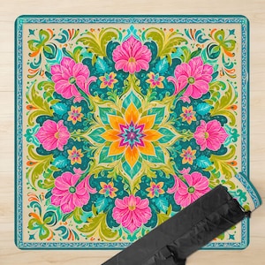 May include: A square mat featuring a vibrant floral mandala pattern with a central yellow and orange star-shaped flower, surrounded by bright pink blossoms, teal leaves, and swirling green foliage, all enclosed within a decorative teal border.