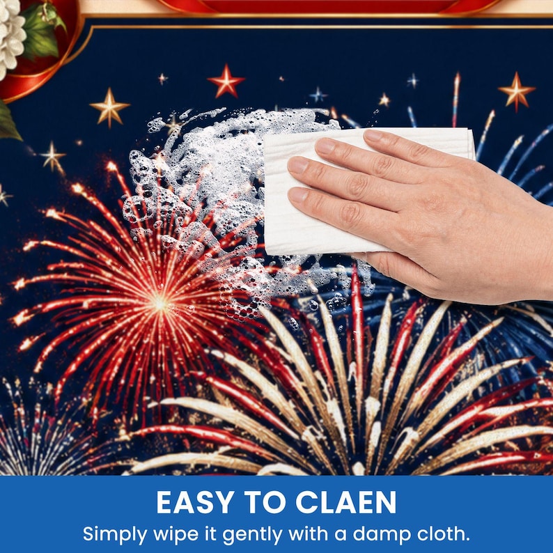 May include: A blue surface with a fireworks design, red and white bursts, and gold stars. A hand wipes the surface with a white cloth, creating suds. Text at the bottom reads "EASY TO CLEAN" and "Simply wipe it gently with a damp cloth."