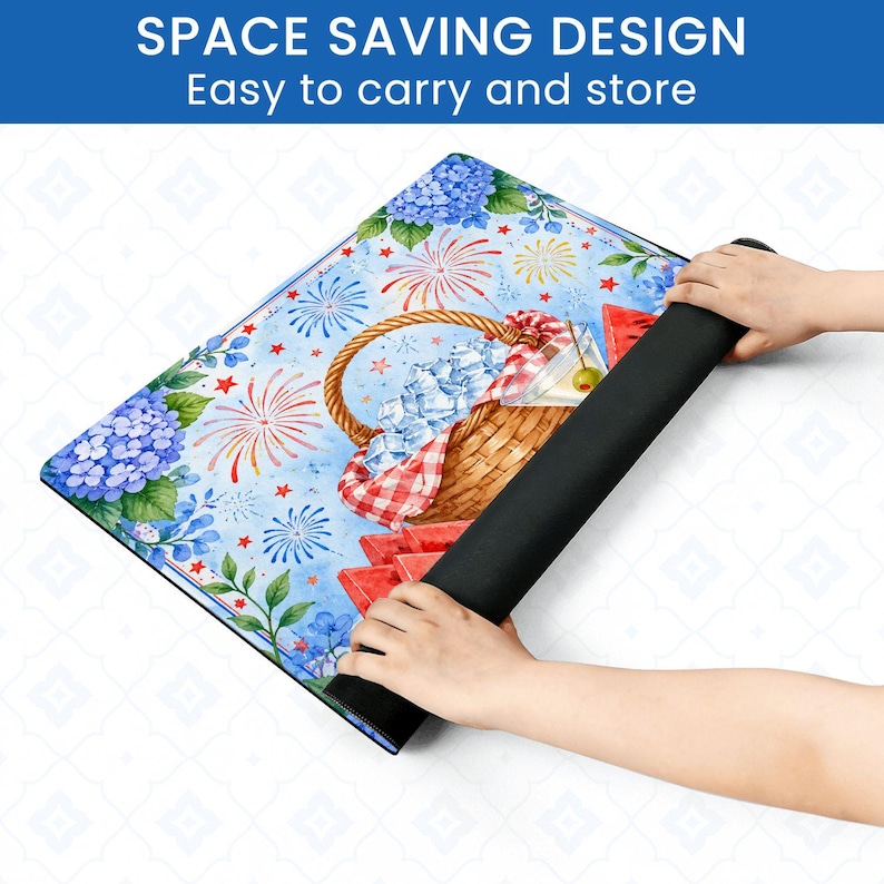 May include: A colorful picnic-themed mat with a blue background, featuring a picnic basket, watermelon slices, and fireworks. The mat is being rolled up, revealing a black underside. Text at the top reads "SPACE SAVING DESIGN Easy to carry and store."