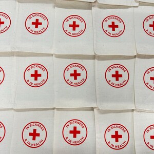 May include: White fabric pouches with a red cross symbol and the text "IN SICKNESS & IN HEALTH" printed in a circular design. The pouches are arranged in a grid pattern, creating a repetitive visual.